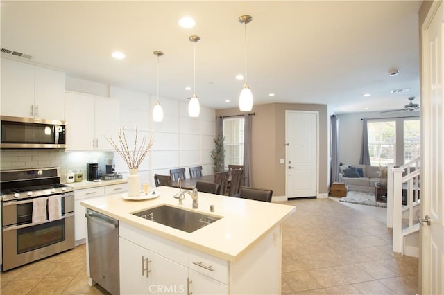 kitchen featuring visible vents, light countertops, decorative backsplash, appliances with stainless steel finishes, and a sink