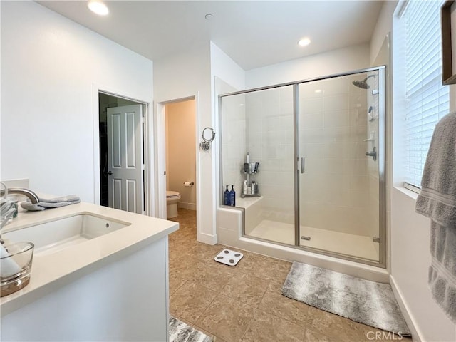 full bath with a stall shower, toilet, baseboards, and a sink