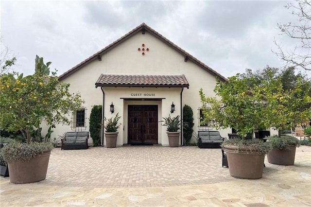 mediterranean / spanish-style home with a tiled roof, a patio area, a garage, and stucco siding