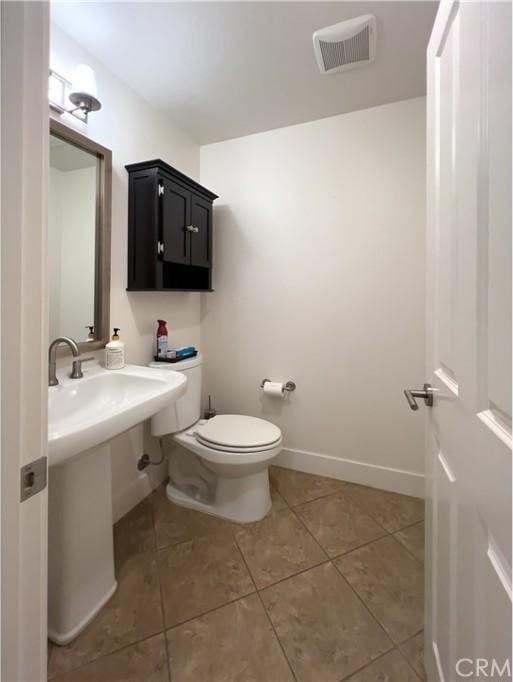 bathroom with tile patterned floors, toilet, baseboards, and visible vents