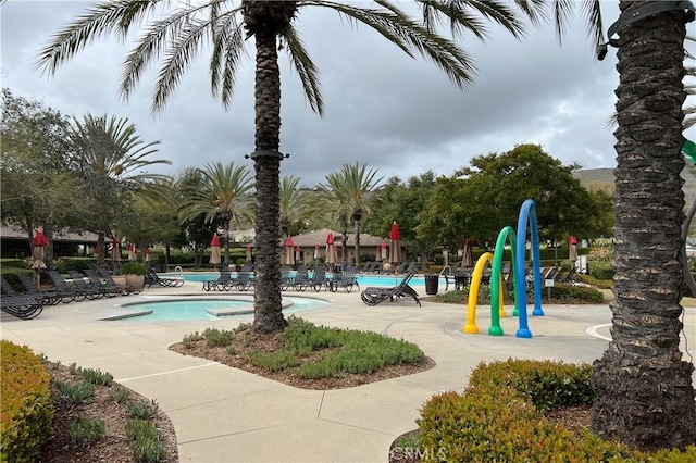 view of jungle gym featuring a patio and a community pool