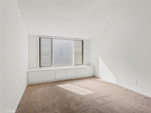 carpeted spare room featuring baseboards and a textured ceiling