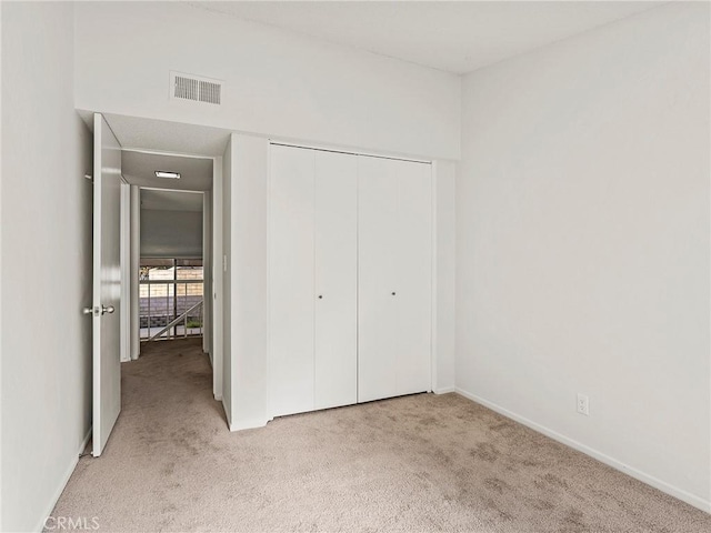 unfurnished bedroom featuring a closet, visible vents, light colored carpet, and baseboards