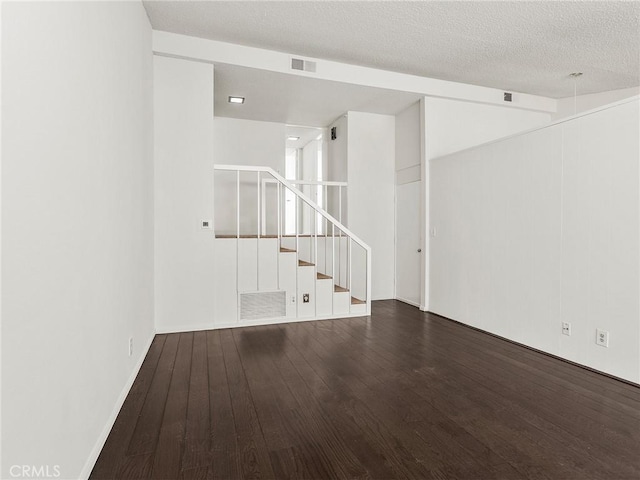 spare room featuring visible vents, a textured ceiling, wood finished floors, and stairs