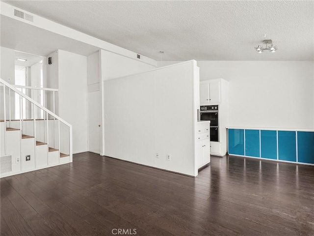 unfurnished living room featuring visible vents, a textured ceiling, stairs, and hardwood / wood-style flooring