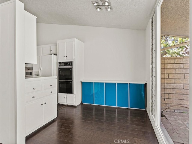 kitchen with lofted ceiling, white refrigerator with ice dispenser, white cabinetry, dobule oven black, and dark wood-style flooring