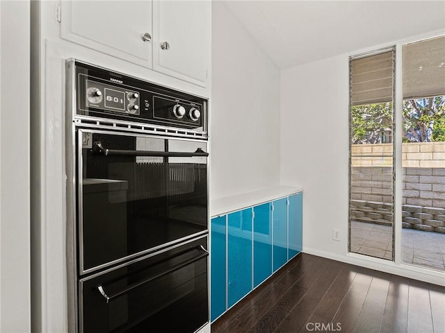 kitchen with a warming drawer, dark wood-type flooring, dobule oven black, white cabinetry, and vaulted ceiling