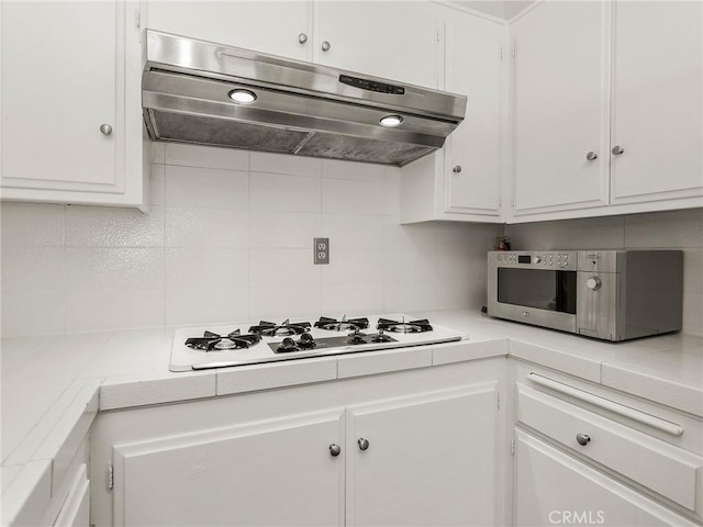 kitchen with under cabinet range hood, decorative backsplash, white cabinetry, and white gas stovetop