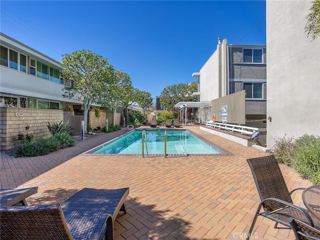 pool with a patio area and fence