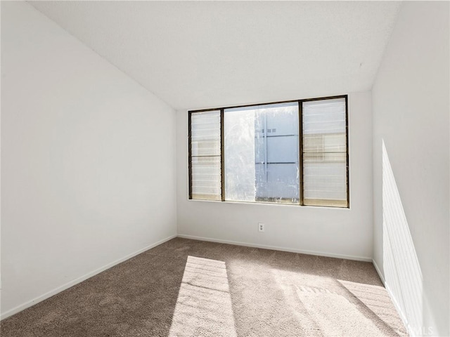 unfurnished room featuring carpet and baseboards