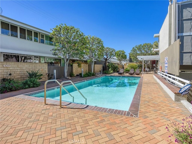 community pool with a patio and fence