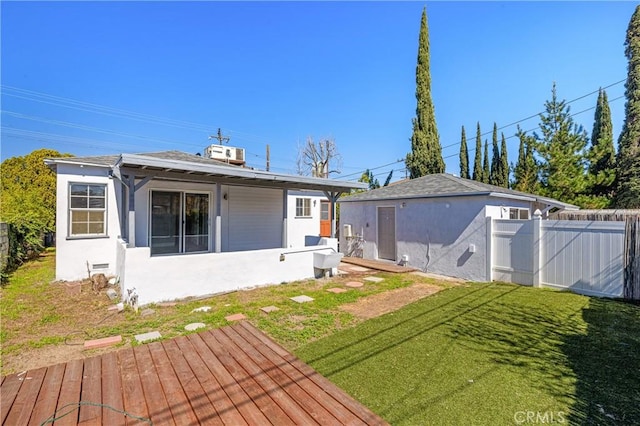 rear view of property with fence, stucco siding, a lawn, a deck, and crawl space