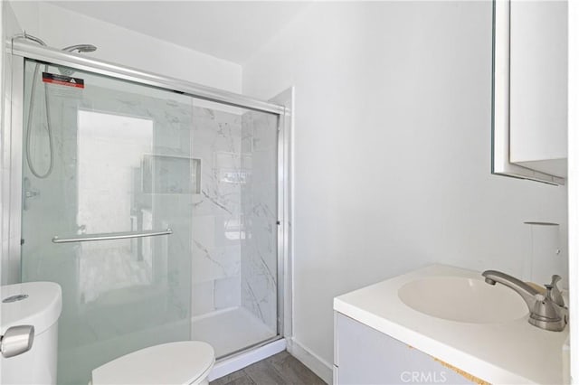 bathroom with a marble finish shower, toilet, wood finished floors, and vanity