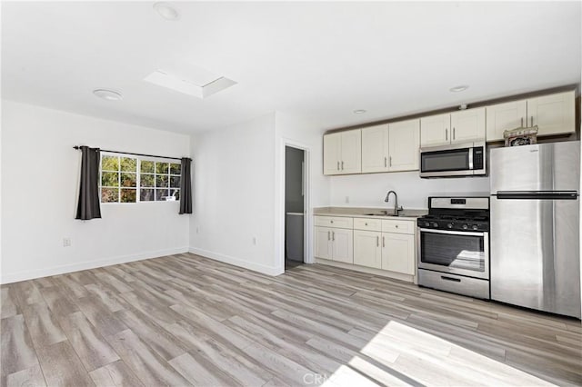 kitchen featuring white cabinetry, light countertops, light wood-style flooring, and stainless steel appliances