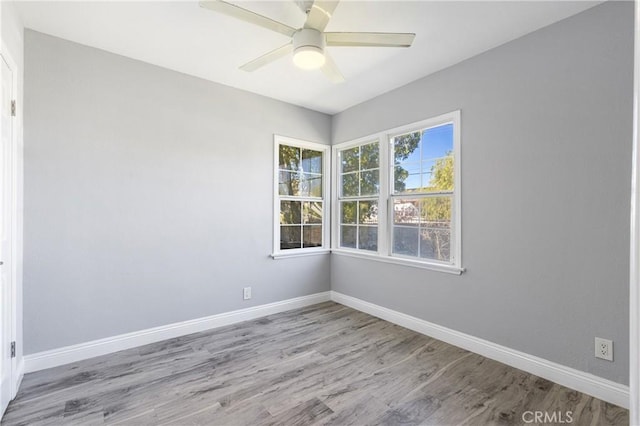 empty room with baseboards, wood finished floors, and a ceiling fan