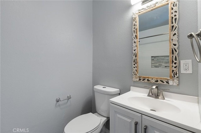 bathroom featuring vanity, toilet, and a textured wall