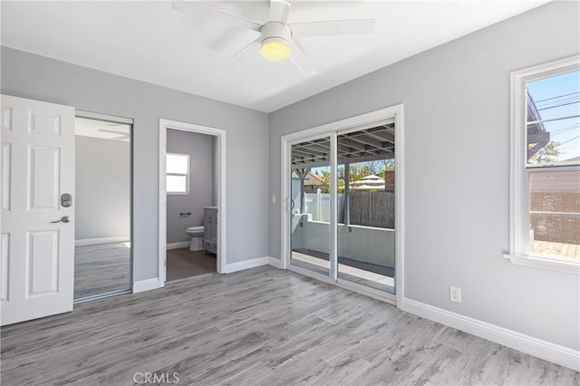 unfurnished bedroom featuring baseboards, multiple windows, wood finished floors, and access to outside