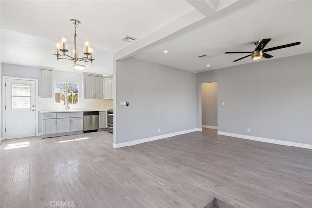 unfurnished living room with visible vents, baseboards, ceiling fan with notable chandelier, and light wood finished floors