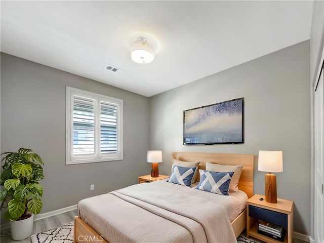 bedroom with wood finished floors, visible vents, and baseboards