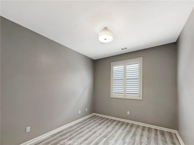 empty room with visible vents, baseboards, and light wood-style floors