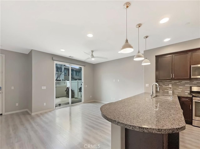 kitchen with tasteful backsplash, light wood finished floors, stainless steel appliances, and a sink