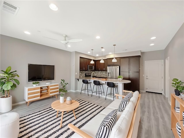 living room with visible vents, recessed lighting, light wood-style floors, baseboards, and ceiling fan