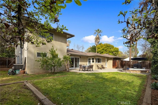 back of property featuring stucco siding, a lawn, a patio area, and fence