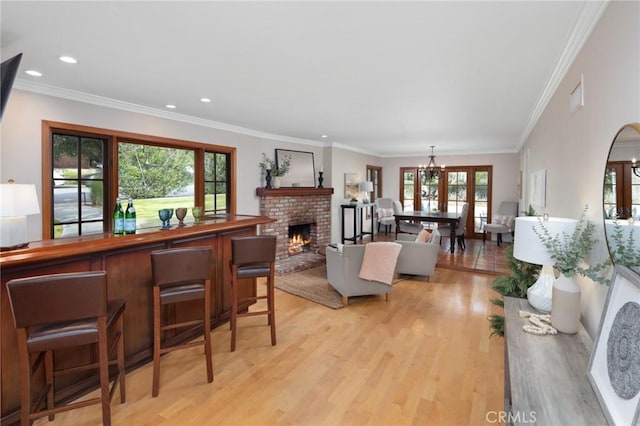 living room with visible vents, light wood finished floors, recessed lighting, crown molding, and a fireplace