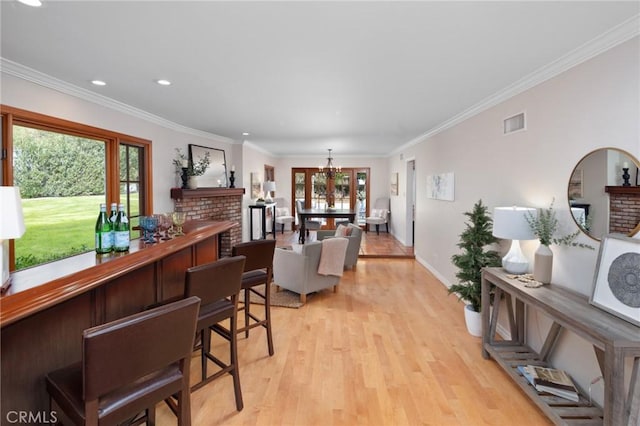 interior space with a fireplace, visible vents, light wood finished floors, and ornamental molding