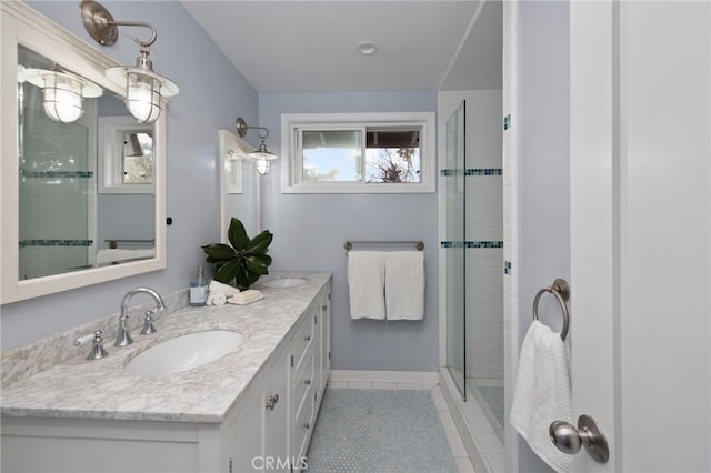 full bath featuring a shower stall, baseboards, double vanity, tile patterned floors, and a sink