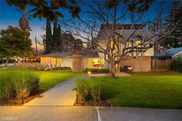 view of front of property featuring stucco siding, a lawn, concrete driveway, and fence