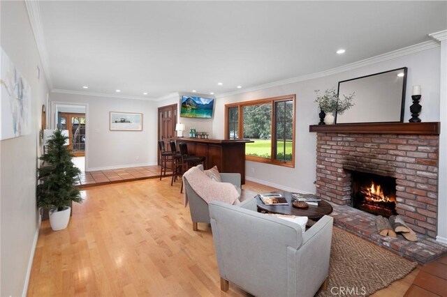 living room featuring baseboards, light wood finished floors, recessed lighting, a fireplace, and ornamental molding