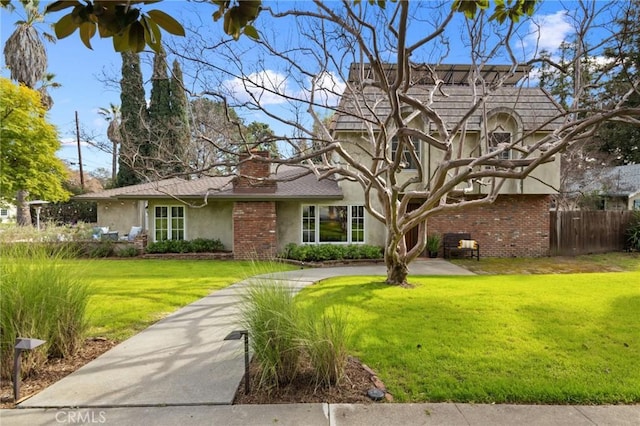view of front of home featuring stucco siding, a chimney, a front yard, and fence