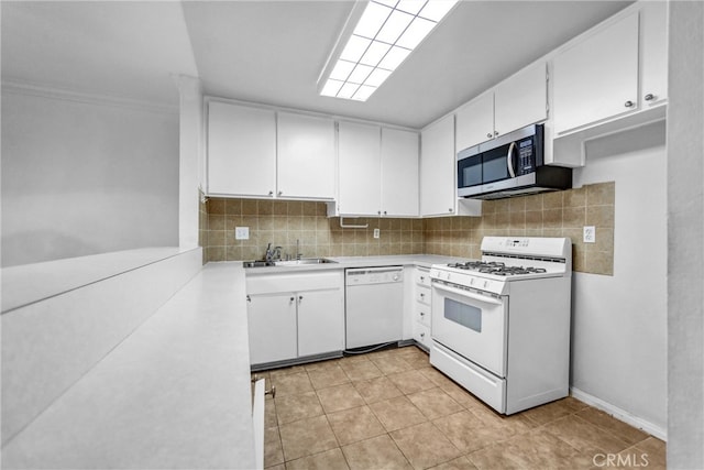 kitchen with decorative backsplash, white appliances, light countertops, and a sink