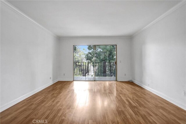 spare room featuring wood finished floors, baseboards, and ornamental molding