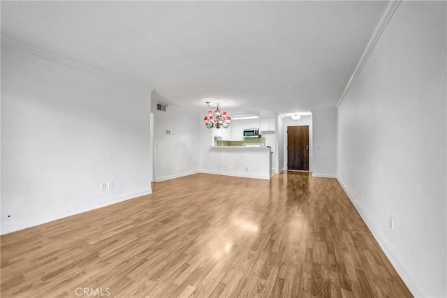 unfurnished living room featuring light wood-type flooring, visible vents, baseboards, and crown molding