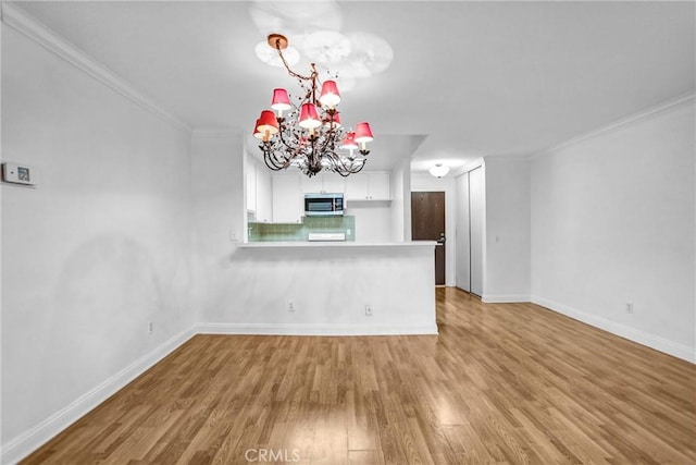 interior space featuring baseboards, a notable chandelier, wood finished floors, and crown molding