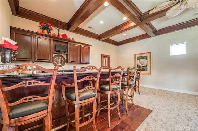 kitchen with baseboards, visible vents, coffered ceiling, a breakfast bar, and beam ceiling