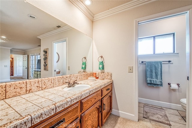 bathroom featuring toilet, vanity, baseboards, and ornamental molding