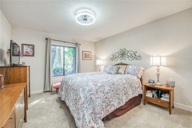 bedroom featuring light carpet, a textured ceiling, and baseboards