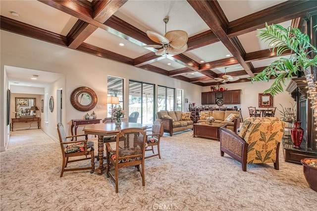 dining area featuring light carpet, beamed ceiling, coffered ceiling, and a ceiling fan