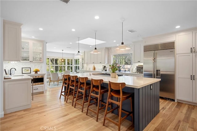 kitchen featuring light countertops, white cabinets, light wood-type flooring, and stainless steel built in refrigerator