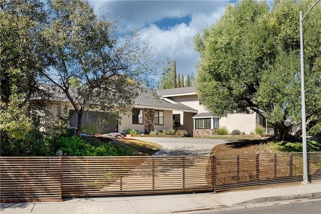 view of front of house featuring a fenced front yard, stucco siding, and decorative driveway