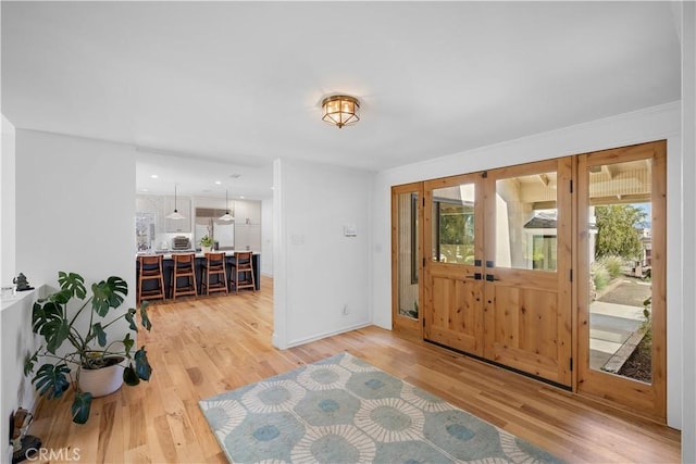 foyer entrance with light wood-style flooring, plenty of natural light, and french doors