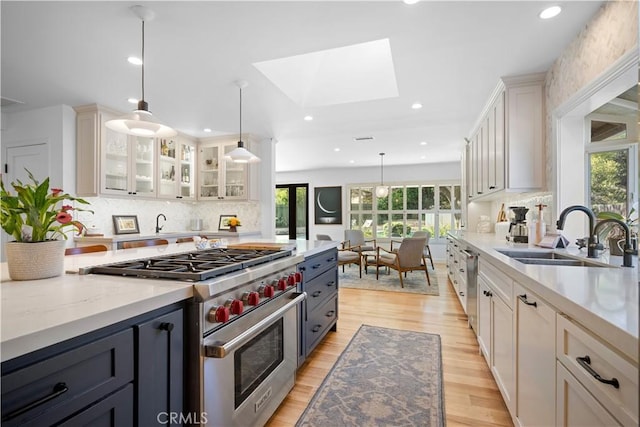 kitchen with a sink, plenty of natural light, stainless steel stove, and a skylight