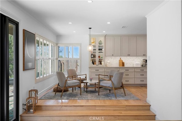 sitting room with recessed lighting, a healthy amount of sunlight, ornamental molding, and wood finished floors