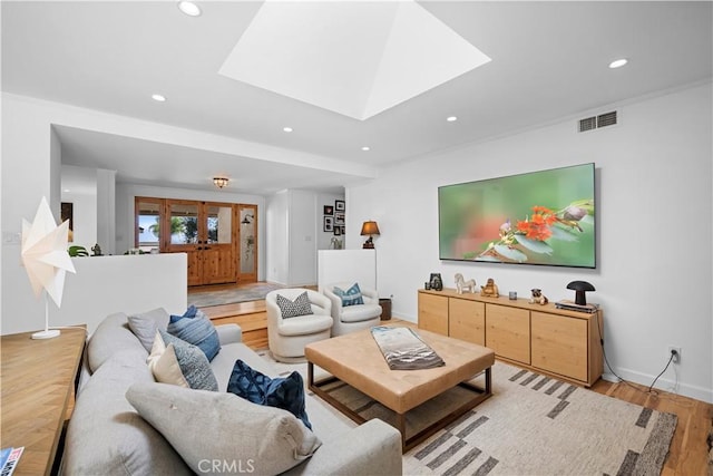 living area featuring baseboards, visible vents, a skylight, recessed lighting, and light wood-type flooring