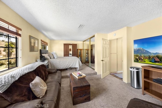 carpeted bedroom with visible vents, a closet, and a textured ceiling