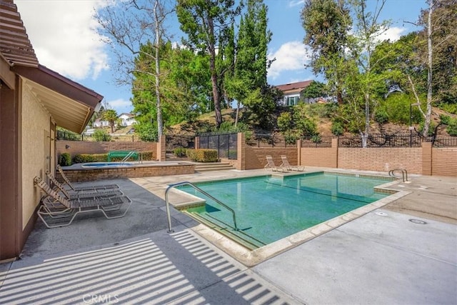 pool featuring an in ground hot tub, a fenced backyard, and a patio