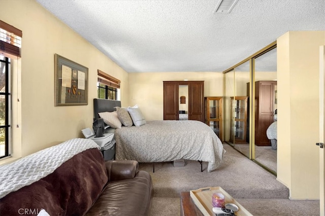 bedroom featuring carpet flooring, visible vents, a closet, and a textured ceiling